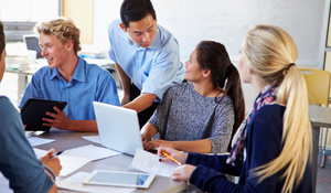 Teacher instructing older students while they are working on a project.