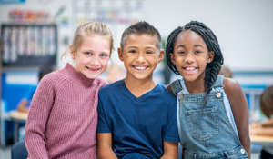 Three diverse students posing in their classroom