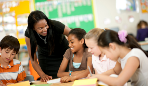 Diverse Student in a Classroom working with their teacher on a project