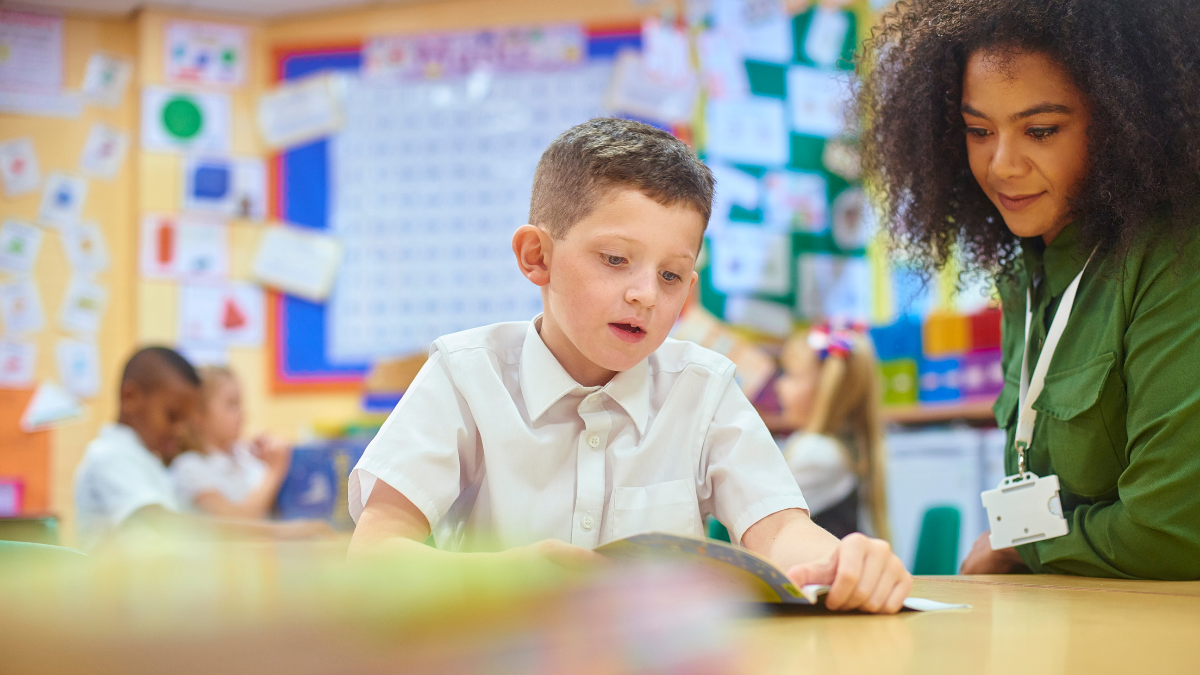 Teacher working with young k-12 student on their work together in the classroom